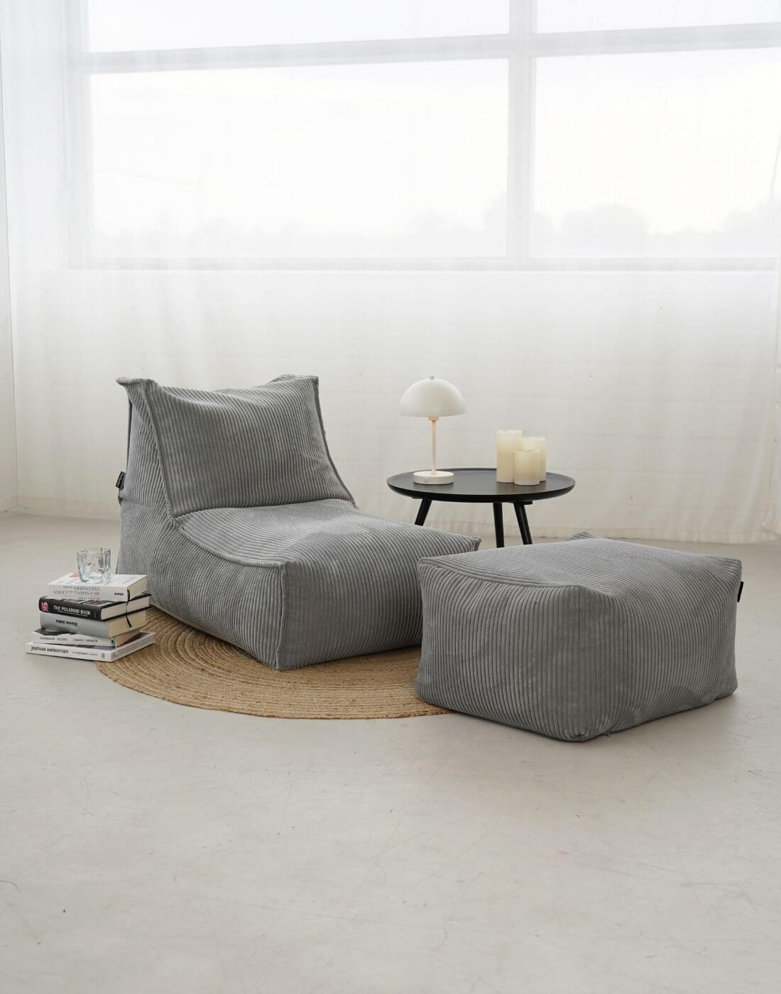 Sitzsack Bean Bag aus Cord 'Der Gelassene' auf runden braunen Teppich mit Couchtisch und Bücherstapel daneben 